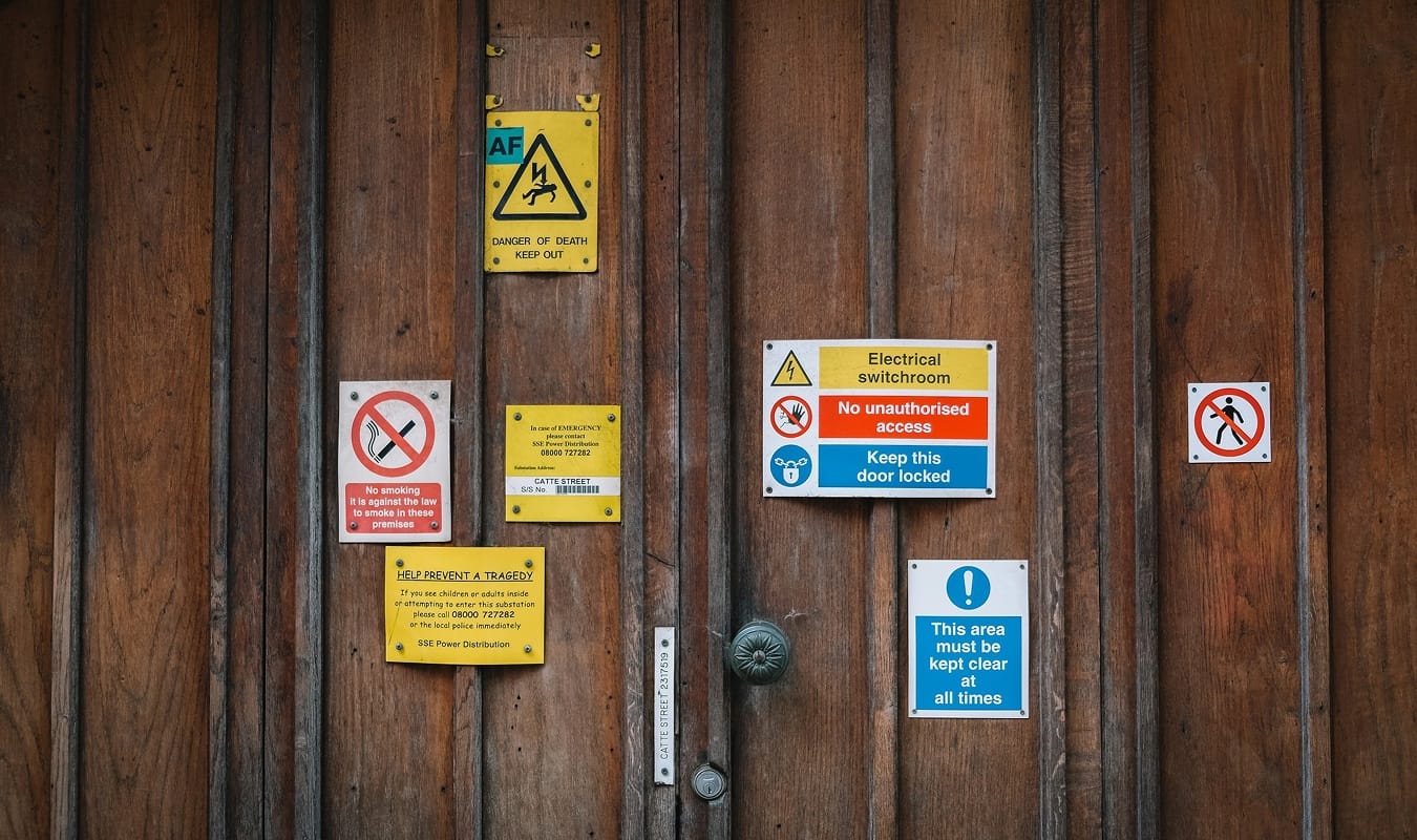 A wooden door covered in warning signs, standing in for design's real job: catching every wrong direction early