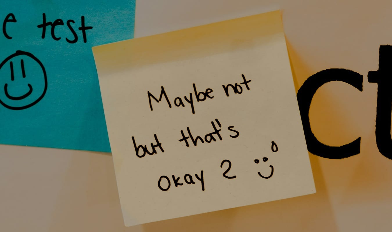 Sticky note reading "Maybe not, but that's okay," a reminder that honest validation beats comfortable answers